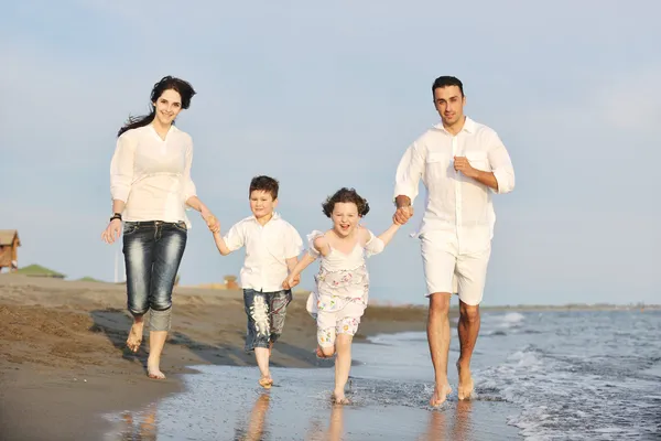 年轻快乐的家庭日落时在海滩上玩得开心 — 图库照片