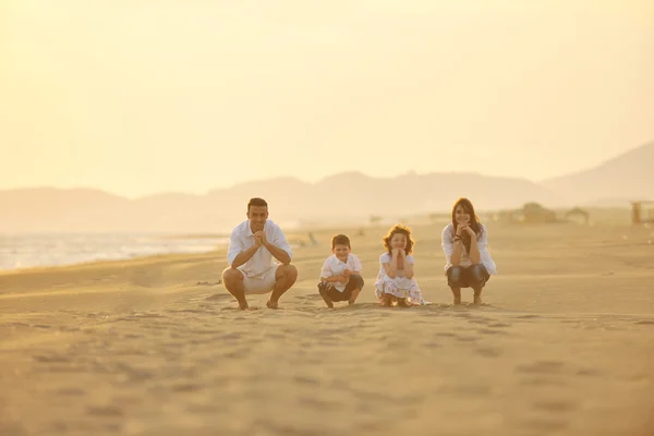 Щаслива молода сім'я розважається на пляжі на заході сонця — стокове фото