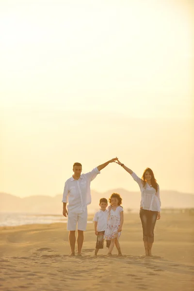 Szczęśliwa młoda rodzina baw się na plaży o zachodzie słońca — Zdjęcie stockowe