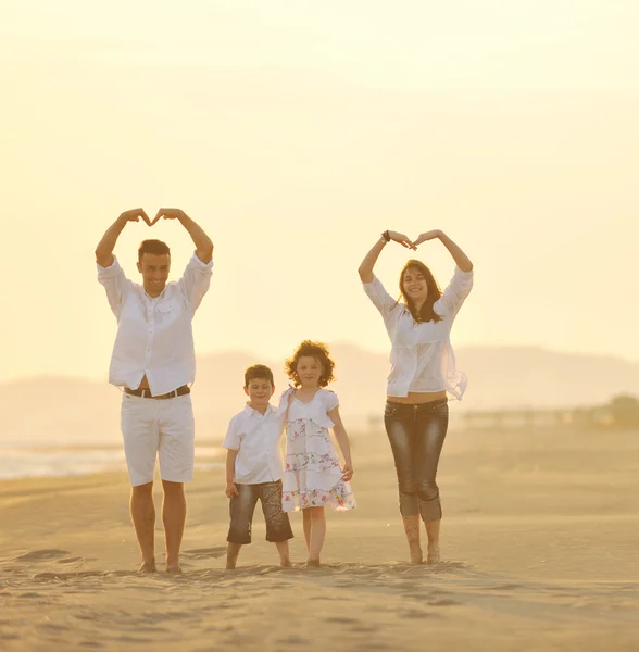 Glückliche junge Familie hat Spaß am Strand bei Sonnenuntergang — Stockfoto