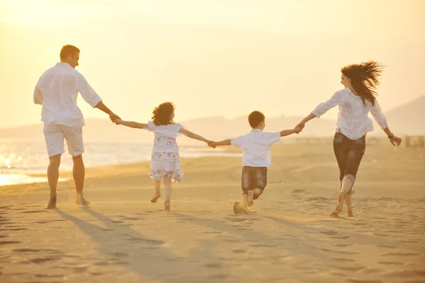 Feliz familia joven divertirse en la playa al atardecer — Foto de Stock