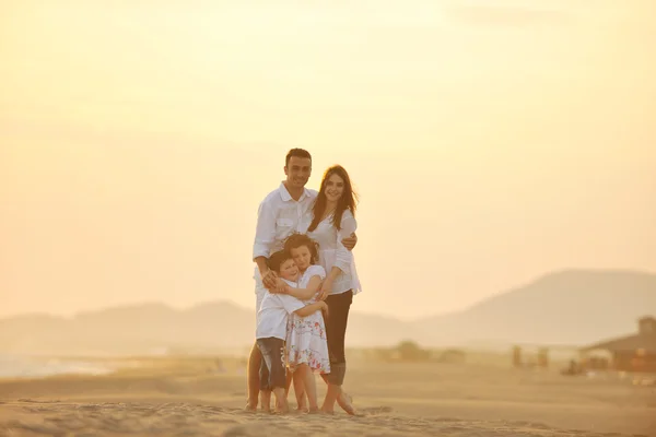 Счастливая молодая семья веселится на пляже на закате — стоковое фото