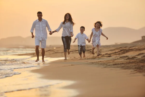 Szczęśliwa młoda rodzina baw się na plaży o zachodzie słońca — Zdjęcie stockowe