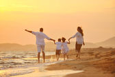 glückliche junge Familie hat Spaß am Strand bei Sonnenuntergang