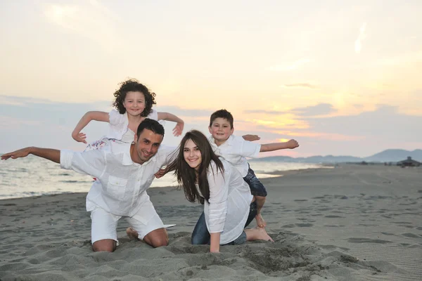 Glad ung familj ha kul på stranden vid solnedgången — Stockfoto