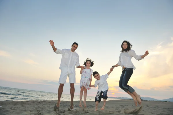 Feliz jovem família se divertir na praia ao pôr do sol — Fotografia de Stock