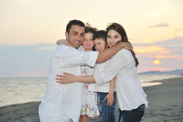 Šťastná mladá rodina bavit na pláži při západu slunce — Stock fotografie
