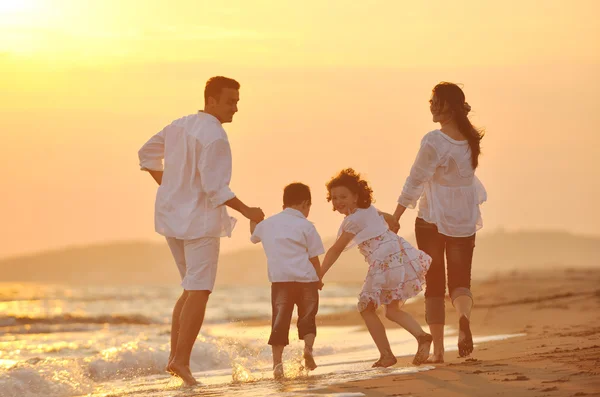 Boldog fiatal család érezd jól magad a strandon naplementekor — Stock Fotó