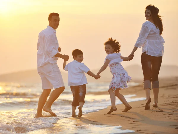 Šťastná mladá rodina bavit na pláži při západu slunce — Stock fotografie