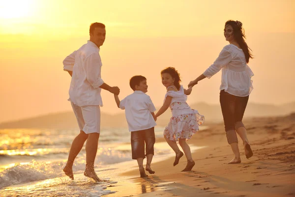 幸せな若い家族は日没時にビーチで楽しんでいます — ストック写真