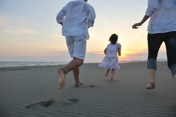 Счастливая молодая семья веселится на пляже на закате — стоковое фото