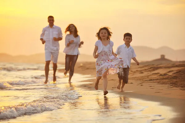 Glückliche junge Familie hat Spaß am Strand bei Sonnenuntergang — Stockfoto