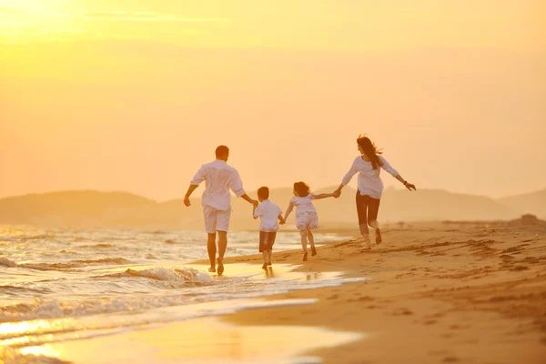 Boldog fiatal család érezd jól magad a strandon naplementekor — Stock Fotó