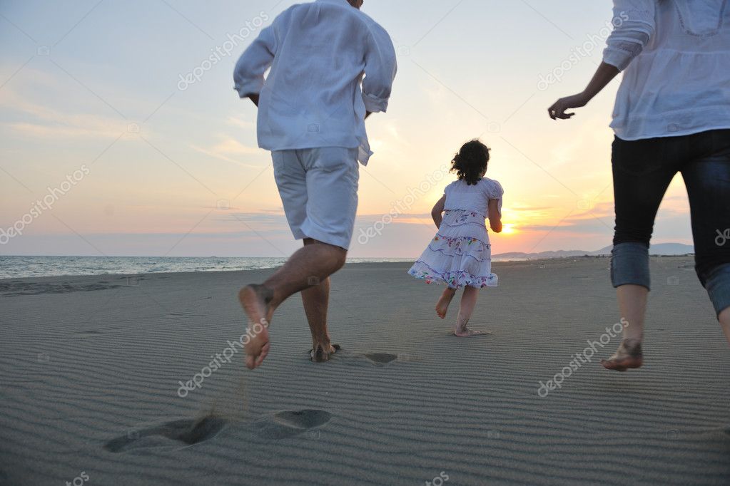 Happy young family have fun on beach run and jump at sunset