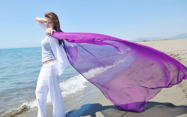 Mooie jonge vrouw op het strand met sjaal — Stockfoto