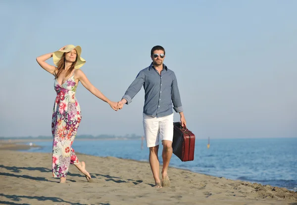 Par på stranden med resväska — Stockfoto