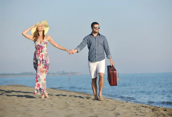 Paar op het strand met reistas — Stockfoto