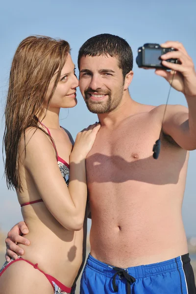 Lyckliga unga par i kärlek tar bilder på stranden — Stockfoto