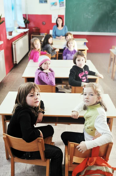 Счастливые дети с учителем в школьном классе — стоковое фото