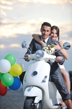 Kumsalda beyaz scooter süren evli bir çift.