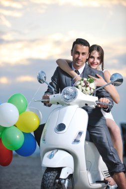 Just married couple on the beach ride white scooter clipart