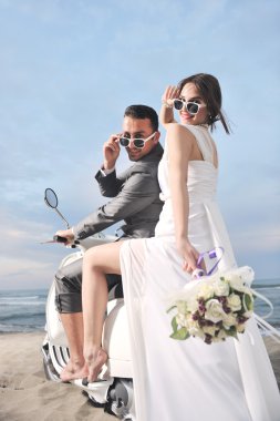 Just married couple on the beach ride white scooter clipart