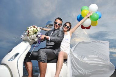 Just married couple on the beach ride white scooter clipart