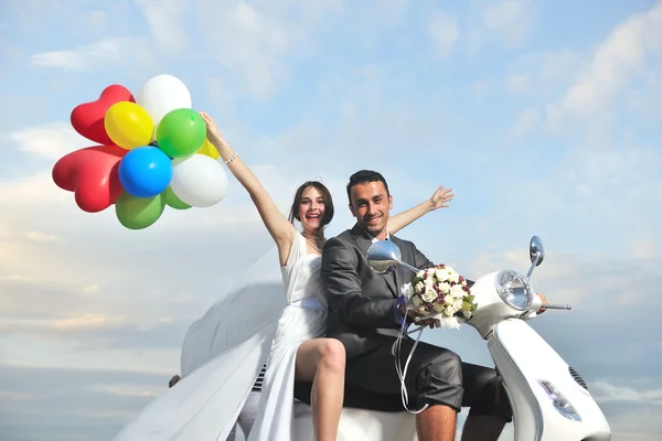 Právě ženatý pár na pláži jízda bílý skútr — Stock fotografie