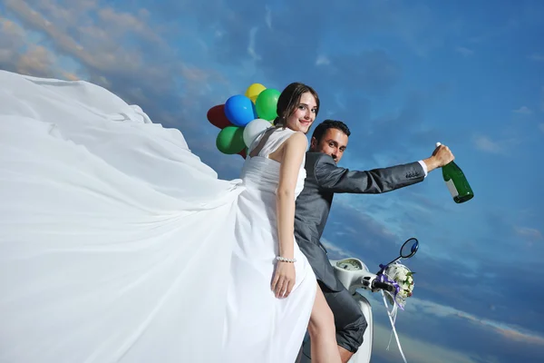 Nygifta par på stranden rida vit skoter — Stockfoto