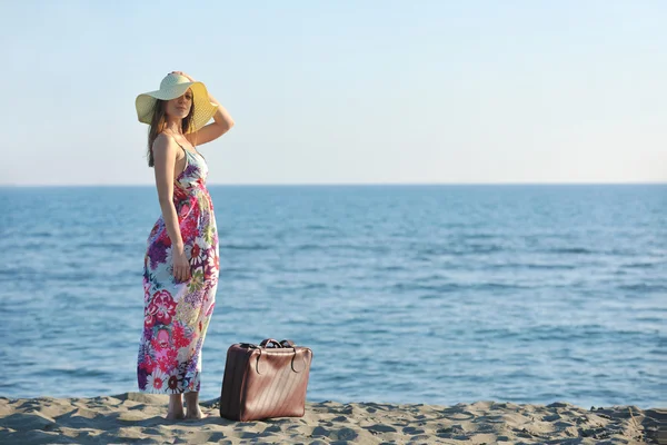Kvinna med resväska på stranden — Stockfoto