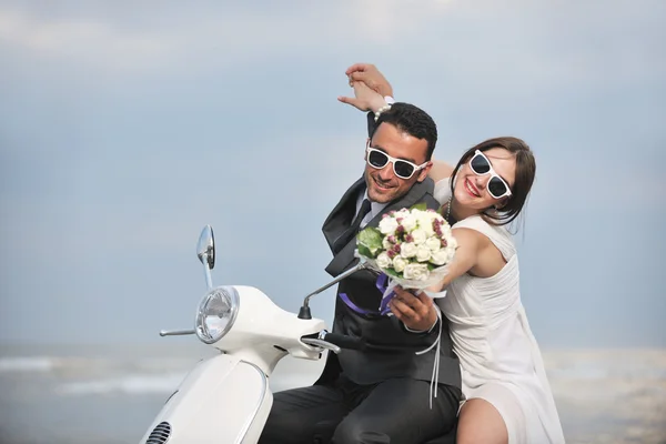 Just married couple on the beach ride white scooter Stock Image