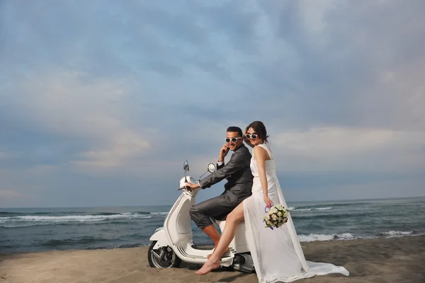 Just married couple on the beach ride white scooter Stock Picture