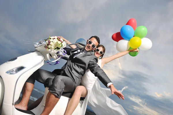 Just married couple on the beach ride white scooter Stock Photo