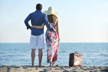 Couple on beach with travel bag clipart