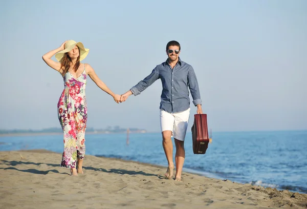 Par på stranden med resväska — Stockfoto
