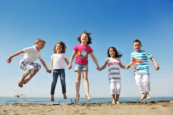 Lyckligt barn gruppen spelar på stranden — Stockfoto