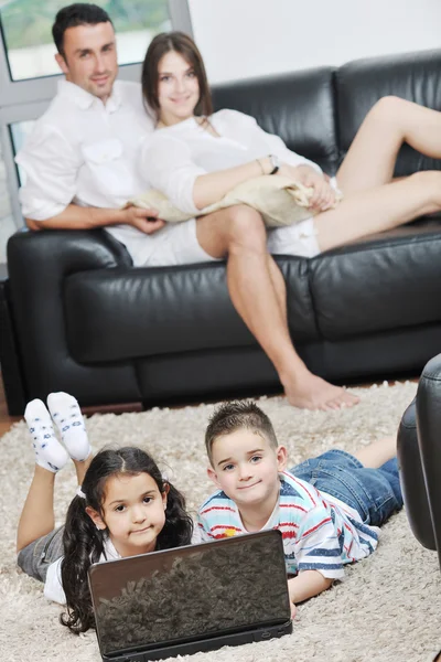 Feliz jovem família se divertir e trabalhar no laptop em casa — Fotografia de Stock