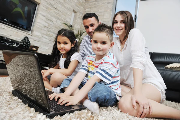 Feliz familia joven divertirse y trabajar en el ordenador portátil en casa —  Fotos de Stock