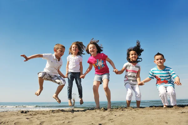 Счастливая детская группа играет на пляже — стоковое фото
