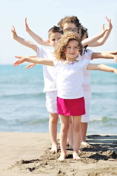 Fröhliche Kindergruppe spielt am Strand — Stockfoto