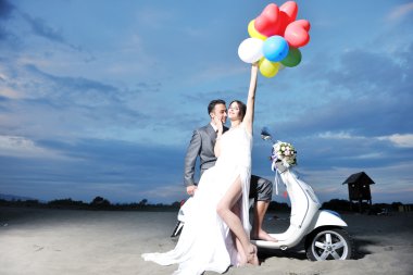 Just married couple on the beach ride white scooter clipart