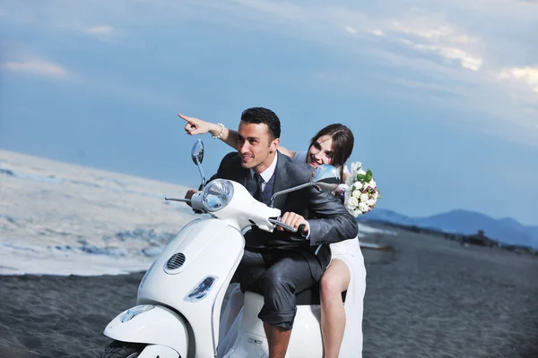 Просто подружня пара на пляжі їздить білим скутером — стокове фото
