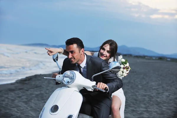 Net getrouwd stel op het strand rijden witte scooter — Stockfoto