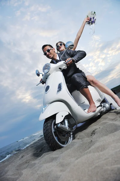 Молодожены на пляже катаются на белом скутере — стоковое фото