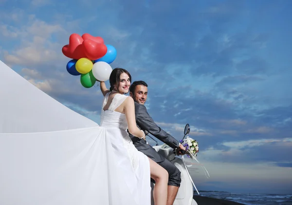 Nygifta par på stranden rida vit skoter — Stockfoto