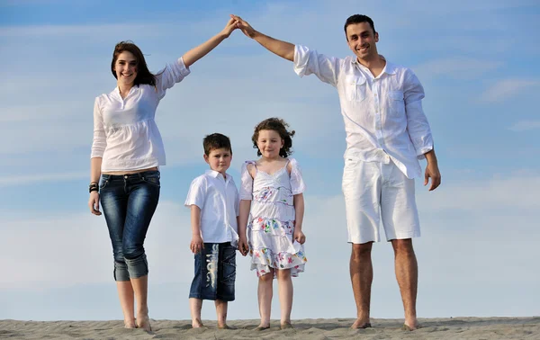 Сім'я на пляжі, що показує домашній знак — стокове фото