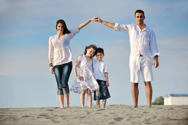 Семья на пляже показывает знак дома — стоковое фото