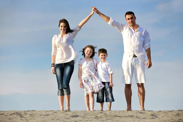 Семья на пляже показывает знак дома — стоковое фото