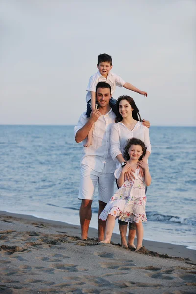 Счастливая молодая семья веселится на пляже — стоковое фото