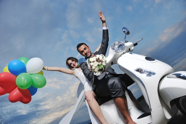 Just married couple on the beach ride white scooter Stock Photo